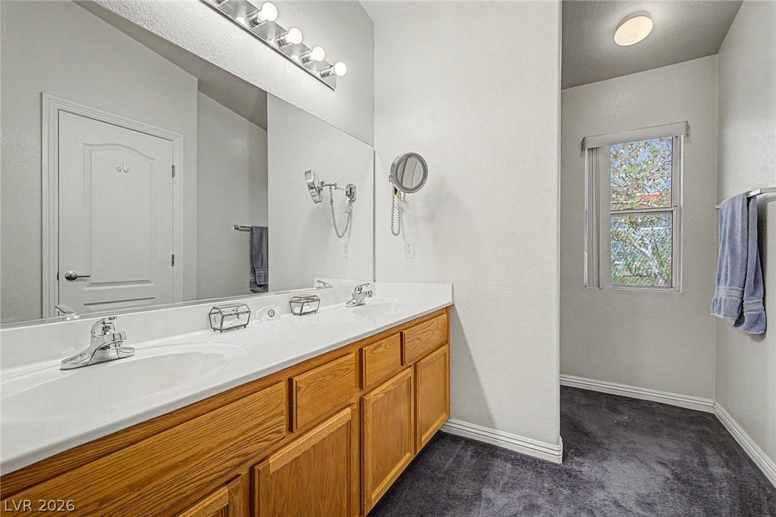 6041 Turning Spoke Trail, #102, Henderson, NV 89011 Plentiful counter space highlights this master bathroom featuring wood cabinetry and carpeted floors.