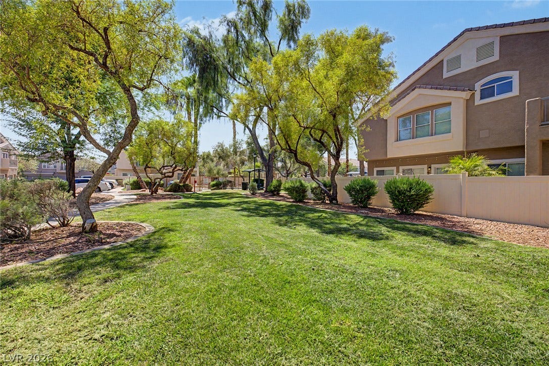 6041 Turning Spoke Trail, #102, Henderson, NV 89011 Mature shade trees and manicured lawns frame the side of the multi-level residential structure.