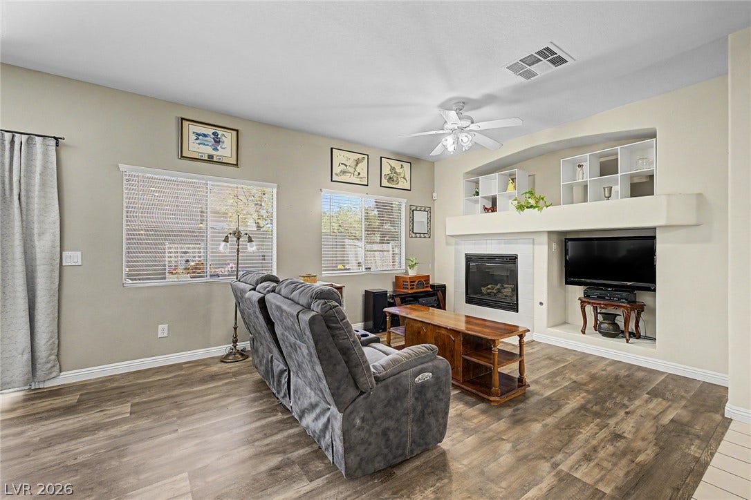 6041 Turning Spoke Trail, #102, Henderson, NV 89011 A cozy fireplace and integrated shelving anchor this comfortable living area with rich wood-look flooring.