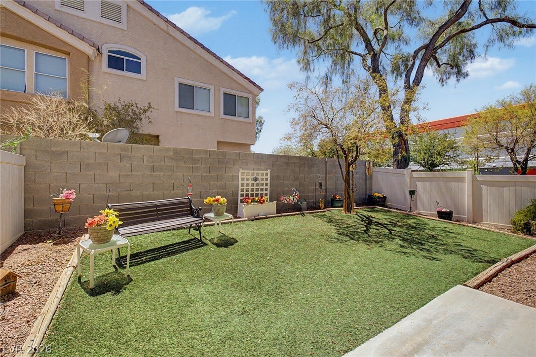 6041 Turning Spoke Trail, #102, Henderson, NV 89011 A private walled backyard features a tidy lawn area and mature shade trees.