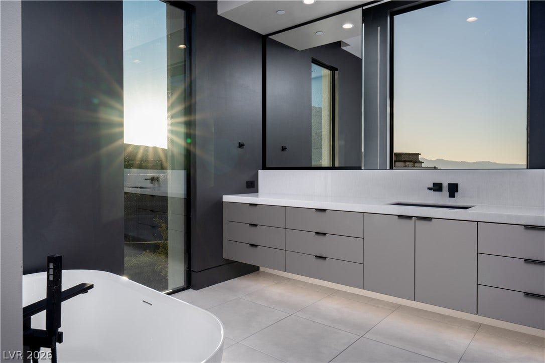 25 Boulderback Drive, Henderson, NV 89012 Floor-to-ceiling windows bathe this modern bathroom in natural light beside a sleek floating vanity.