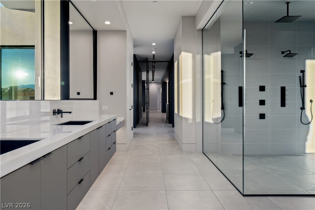 25 Boulderback Drive, Henderson, NV 89012 Clean lines and stone counters define this modern bathroom with an expansive glass shower.
