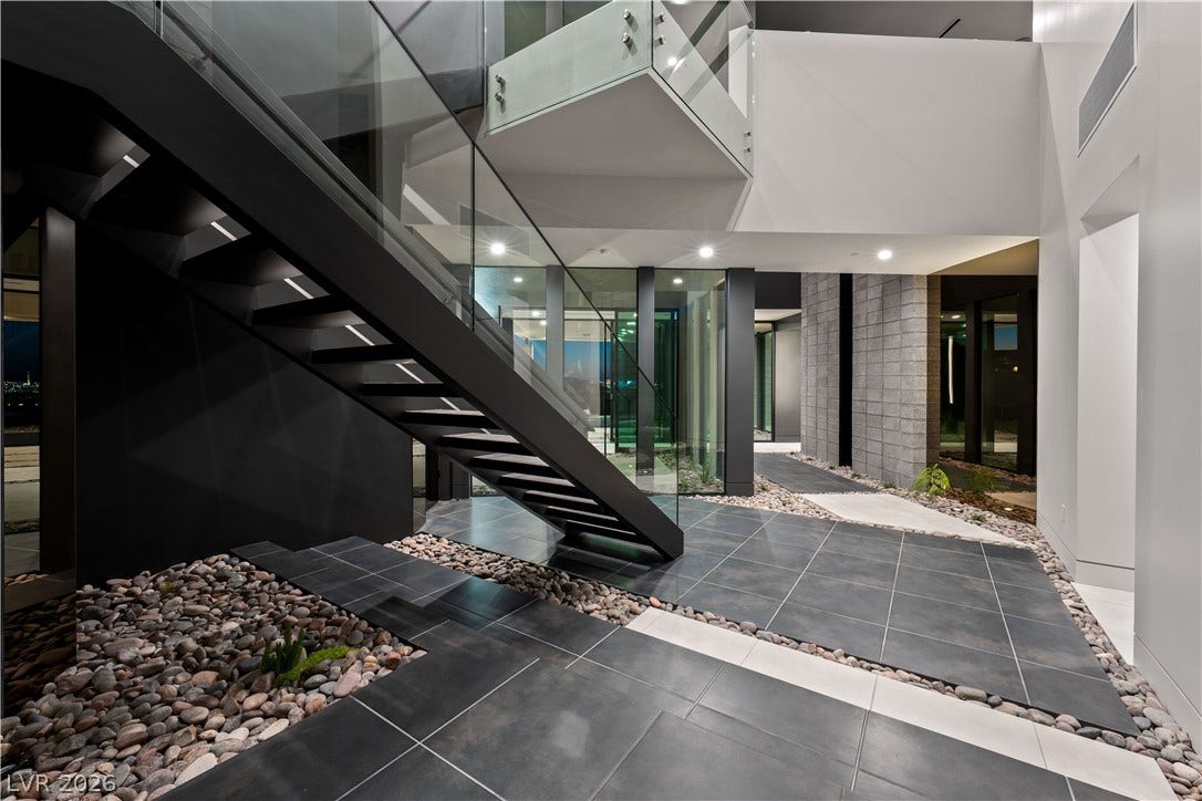 25 Boulderback Drive, Henderson, NV 89012 Dramatic architectural lines define this entry, showcasing a floating staircase with glass railings.