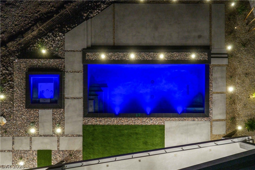 25 Boulderback Drive, Henderson, NV 89012 An aerial perspective showcases a sleek pool and integrated spa illuminated by vibrant blue lighting.