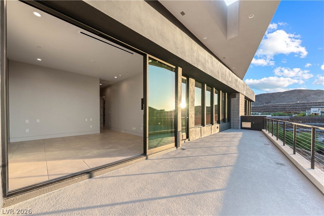 25 Boulderback Drive, Henderson, NV 89012 A spacious concrete balcony opens to interior living spaces through expansive glass doors.