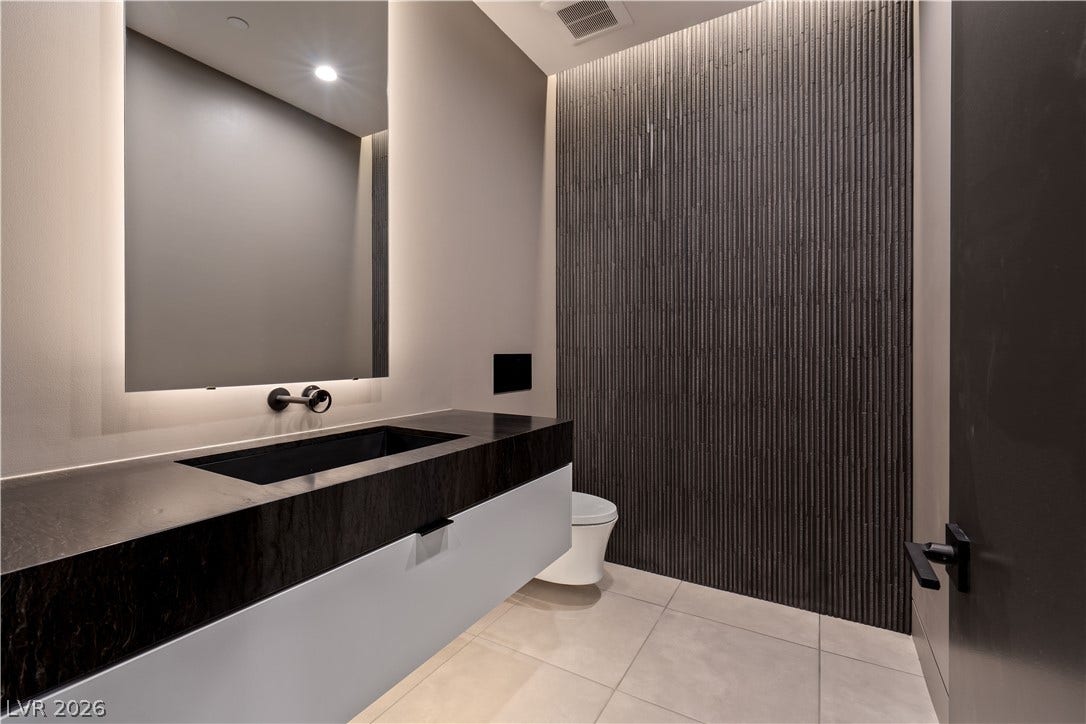 25 Boulderback Drive, Henderson, NV 89012 Textured wall detailing and modern stone surfaces define this powder room.