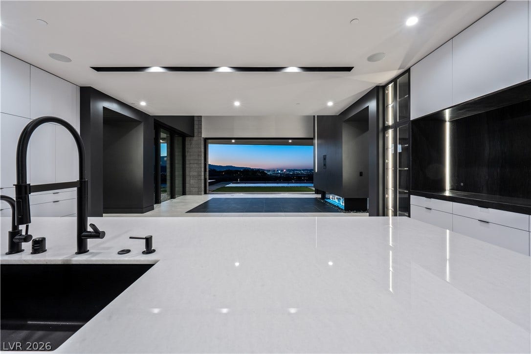 25 Boulderback Drive, Henderson, NV 89012 Gleaming stone countertops and clean lines frame a captivating twilight view of the city.