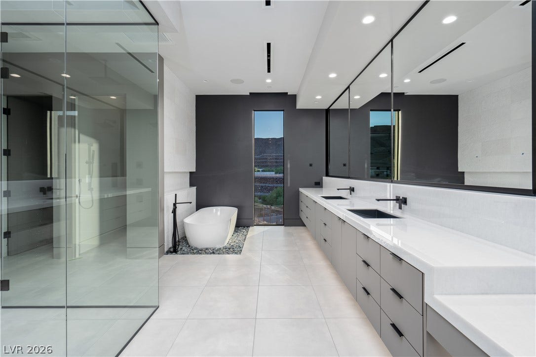 25 Boulderback Drive, Henderson, NV 89012 Sleek modern finishes define this bathroom complete with a glass-enclosed shower and soaking tub.
