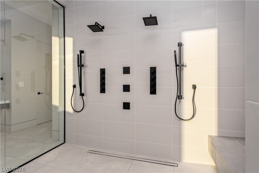 25 Boulderback Drive, Henderson, NV 89012 A glass-enclosed shower showcases modern black fixtures set against light floor-to-ceiling tiling.