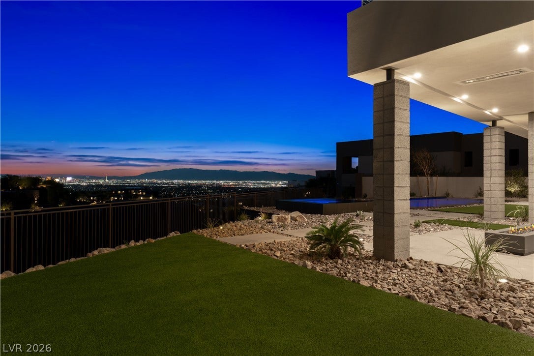 25 Boulderback Drive, Henderson, NV 89012 A sleek covered patio overlooks a manicured lawn with sweeping valley views at dusk.