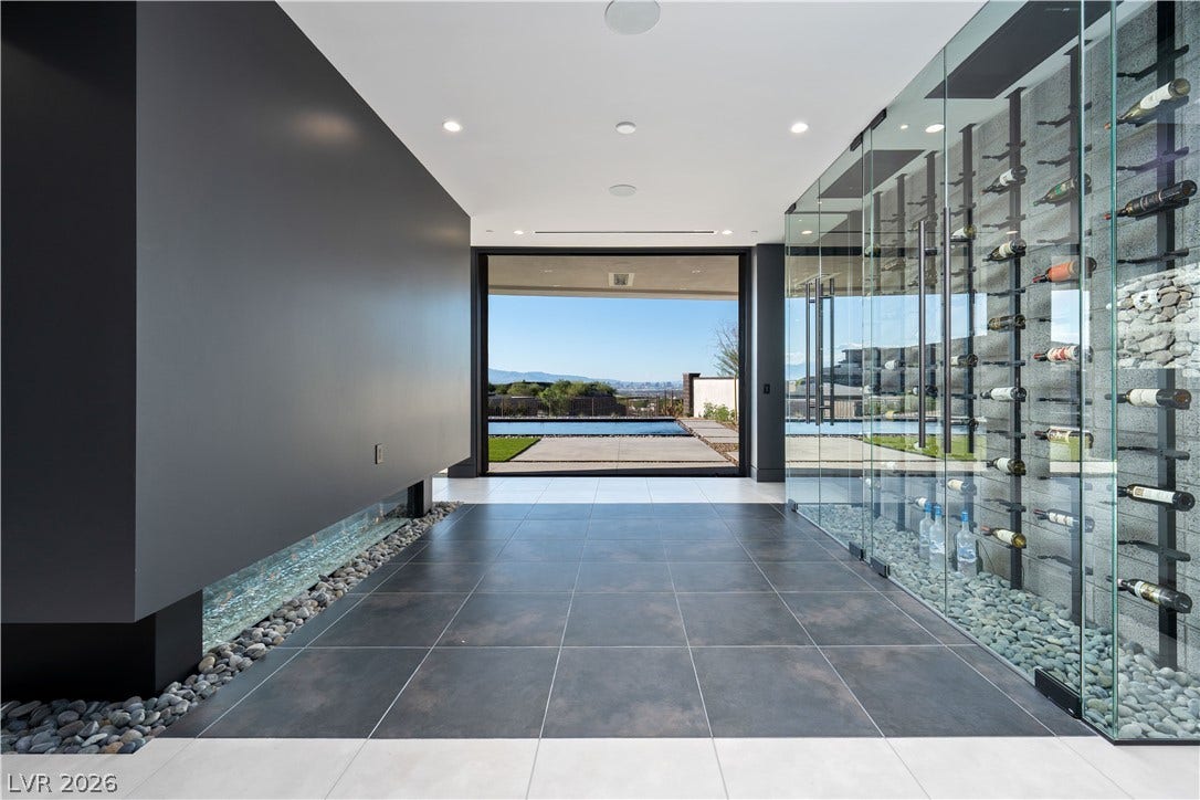 25 Boulderback Drive, Henderson, NV 89012 Floor-to-ceiling glass display walls flank this modern hallway leading to a scenic outdoor patio.