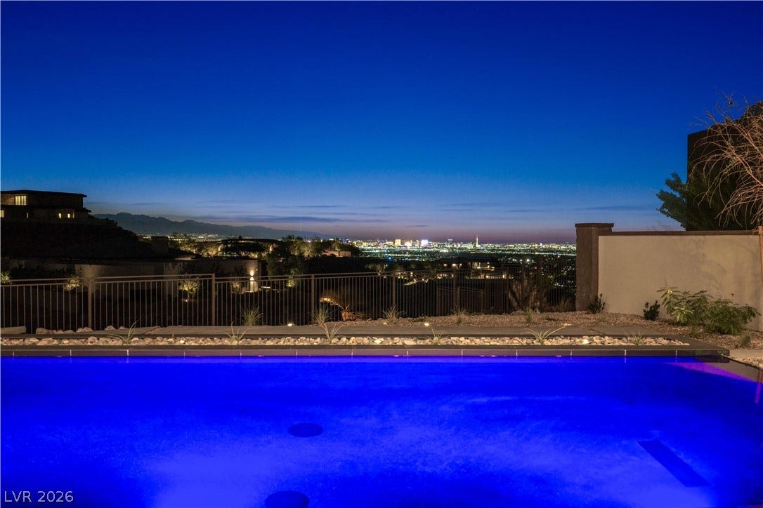 25 Boulderback Drive, Henderson, NV 89012 Glittering city lights frame the horizon beyond a gleaming swimming pool.