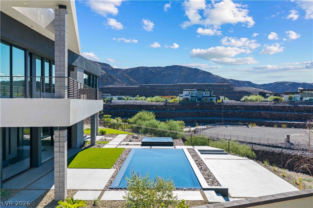 25 Boulderback Drive, Henderson, NV 89012 A geometric pool and stone deck command attention against a rugged mountain backdrop.