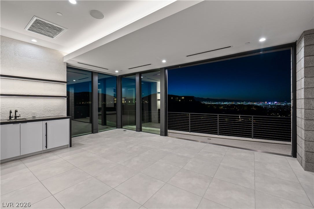 25 Boulderback Drive, Henderson, NV 89012 Massive sliding glass walls open to a covered terrace with views of the city lights.