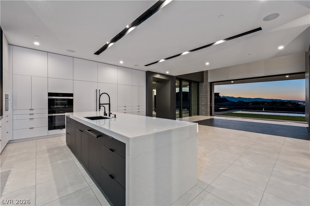 25 Boulderback Drive, Henderson, NV 89012 Sleek modern cabinetry and a waterfall island flow seamlessly to panoramic sunset views.