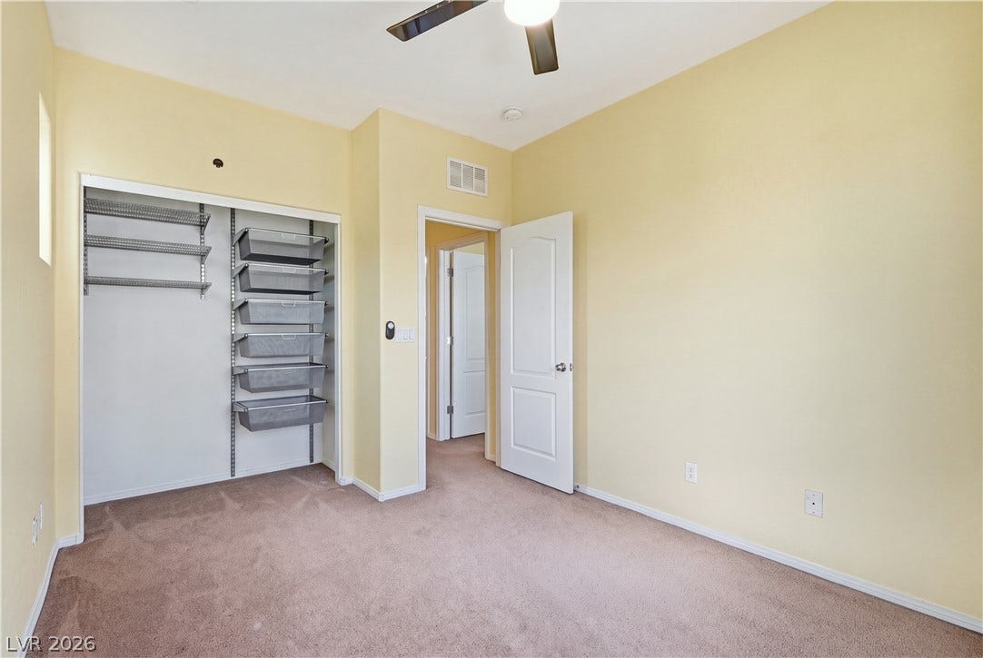 A versatile secondary bedroom features wall-to-wall carpeting and a customizable closet shelving system.