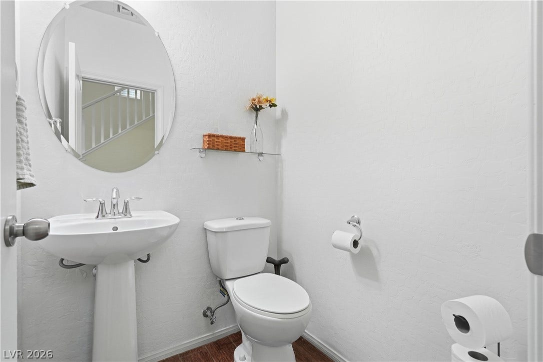 A crisp white powder room includes a classic pedestal sink paired with an oval mirror.