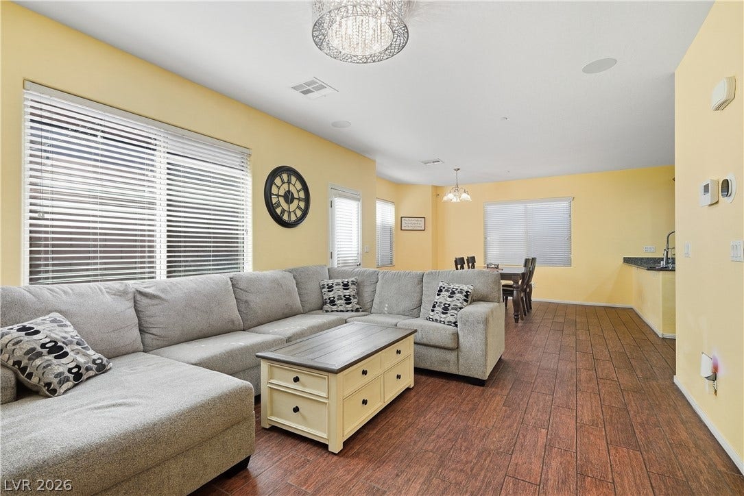 Warm wood-look flooring and natural light from large windows define this open living space.