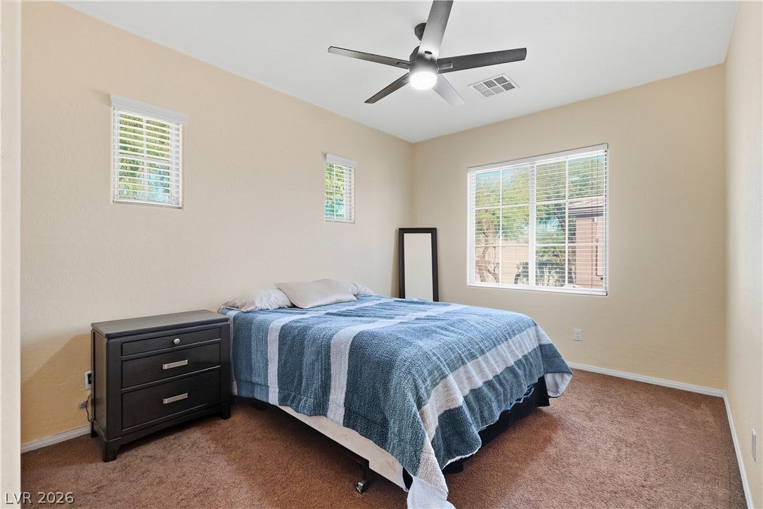 Warm-toned walls and plush carpeting frame a peaceful bedroom illuminated by abundant natural light.