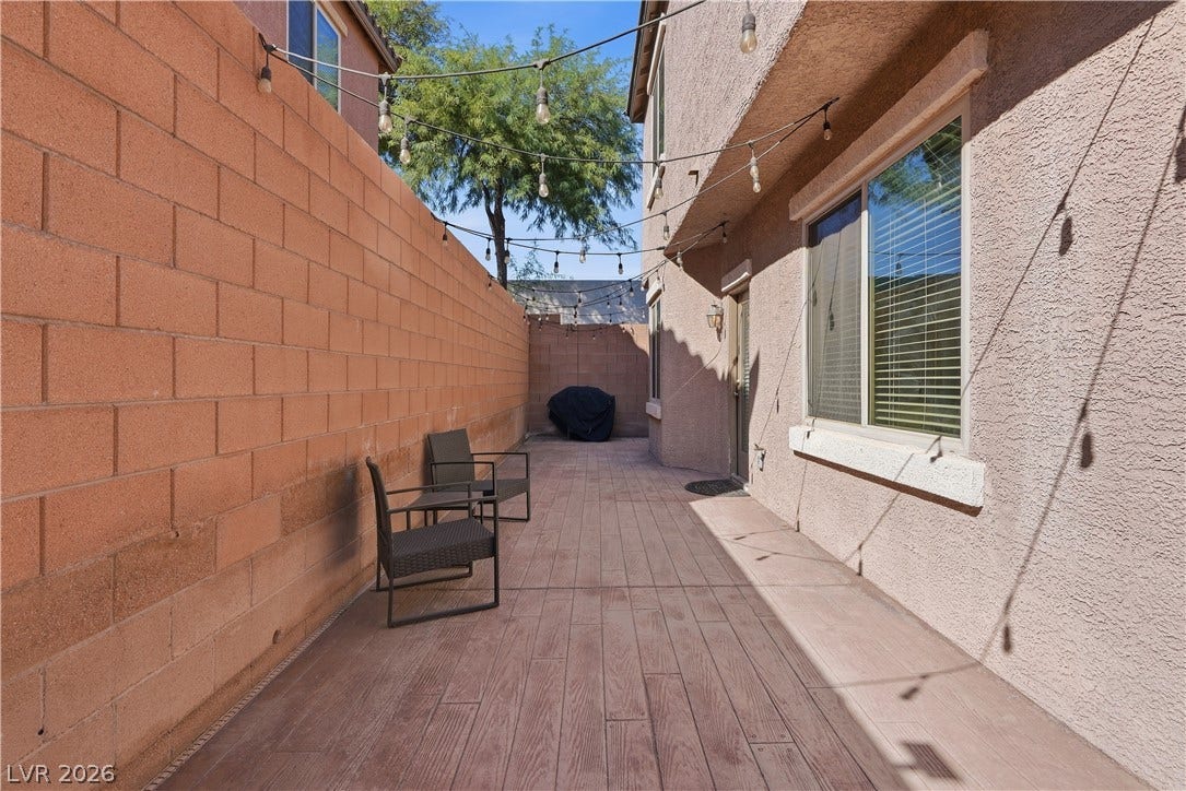 An inviting side patio features durable wood-look flooring bordered by a tall privacy wall.
