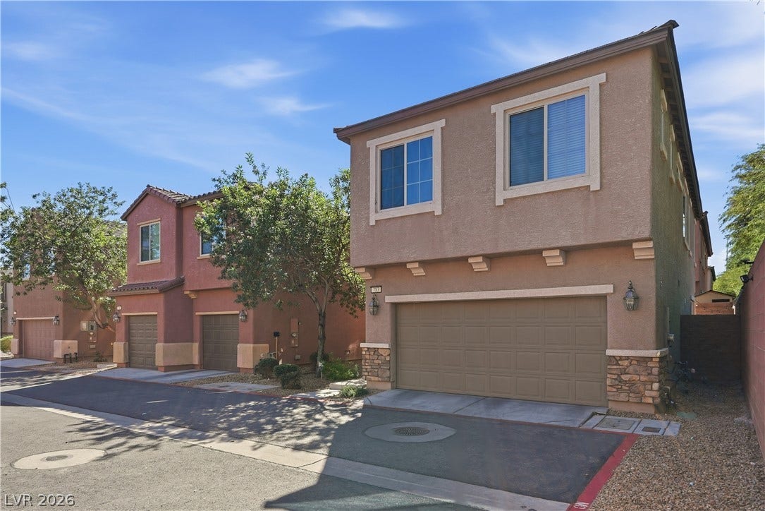 A classic stucco facade features stone accents and a spacious multi-car garage.