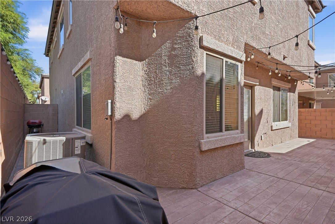 An inviting paved patio area extends along the textured stucco exterior of the home.