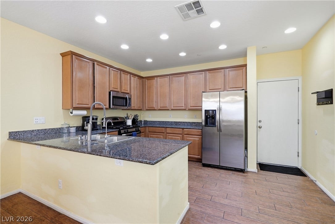 Gleaming granite countertops pair beautifully with ample wood cabinetry in this well-appointed cooking space.