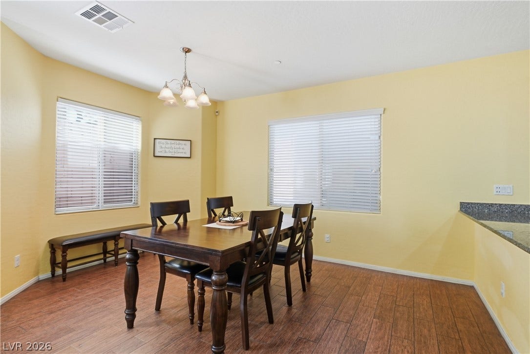 Sunlight streams across rich wood-look flooring in a welcoming dining space.