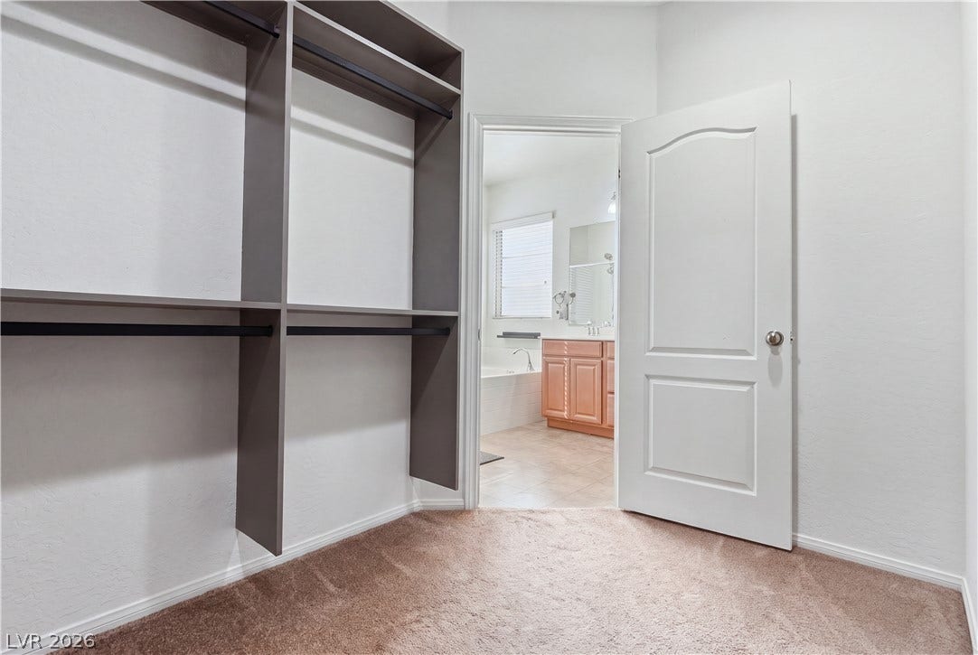 A spacious walk-in closet with built-in shelving transitions smoothly into the master bathroom.