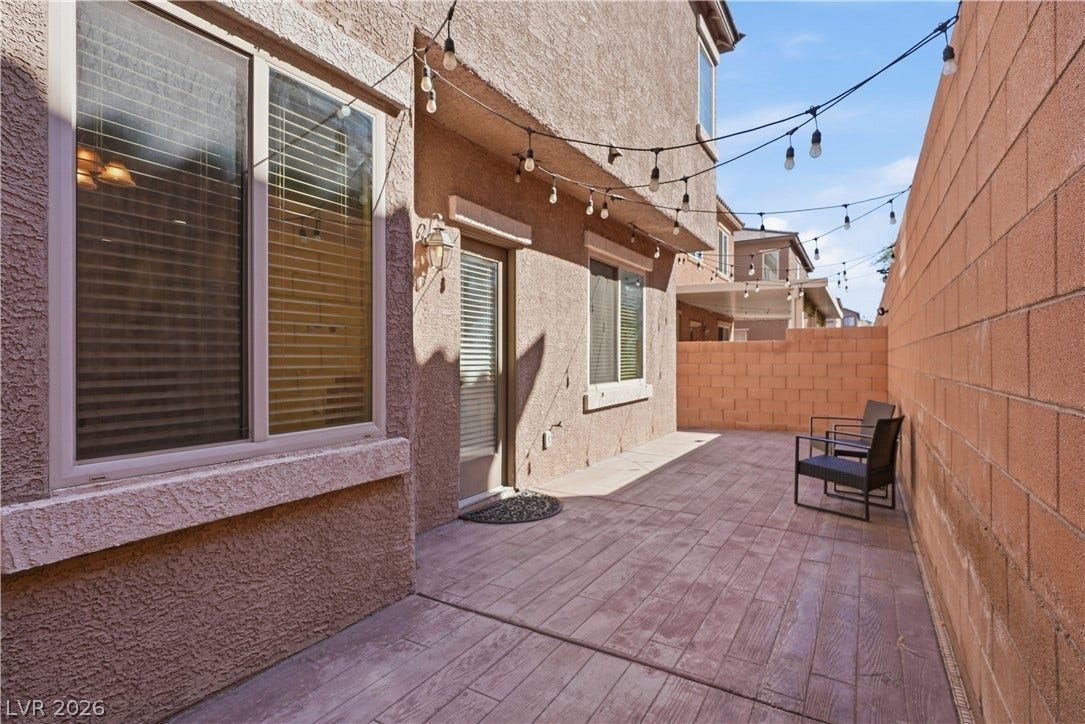 An inviting private courtyard features textured stucco walls and concrete pavers under open skies.