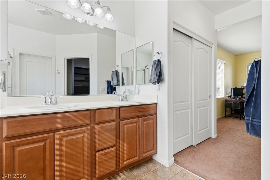 A spacious double vanity offers abundant storage and sleek solid countertops in this modern bathroom.