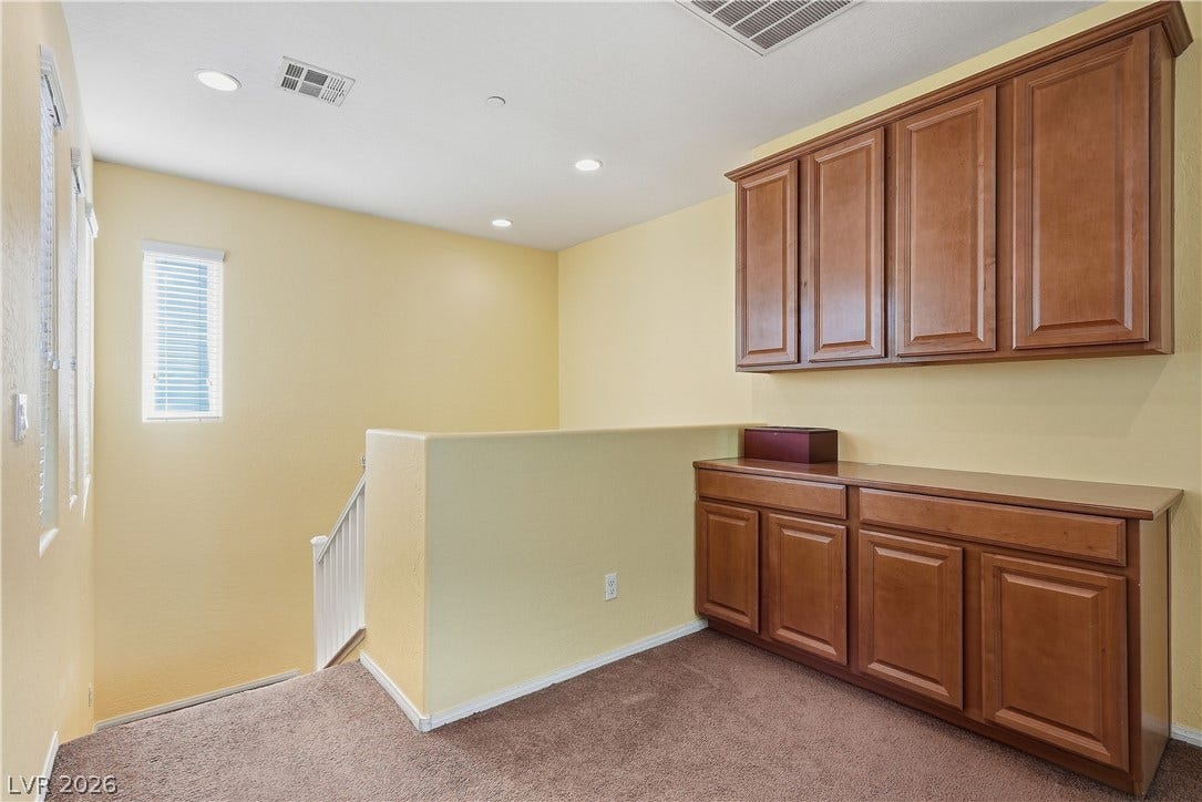 Rich wood cabinetry and soft carpeting define this versatile upper landing space.
