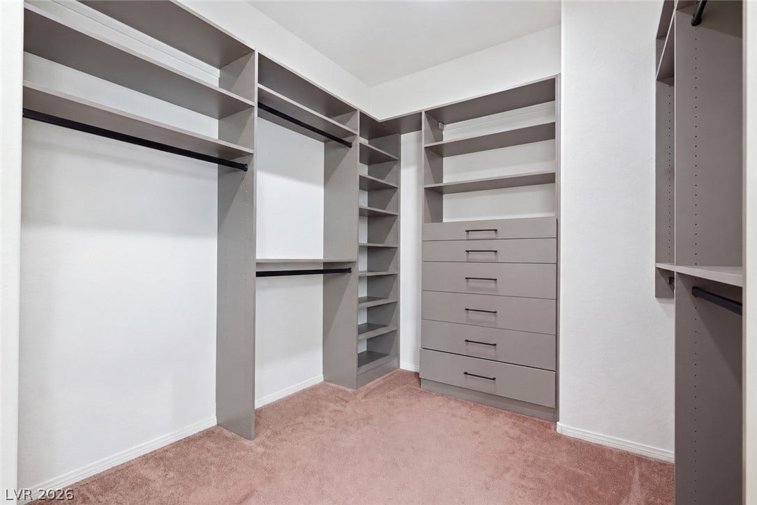 Custom built-in shelving and ample drawer storage maximize space in this carpeted walk-in closet.