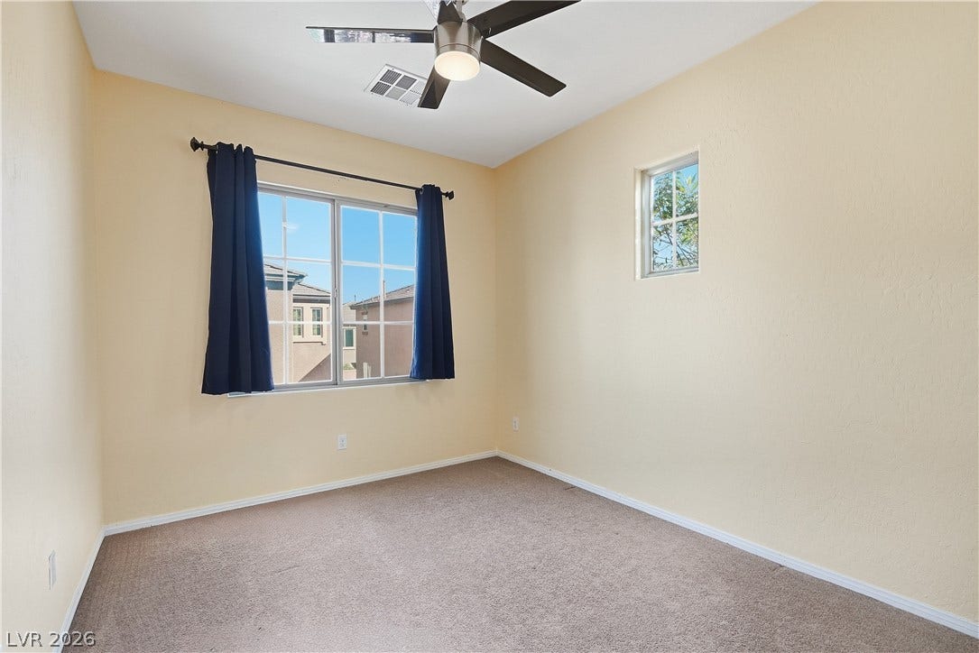 Plentiful natural light streams through multiple windows in this carpeted bedroom.