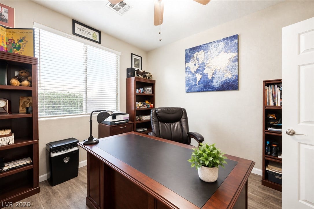 Hardwood floors and a wide window create a comfortable workspace in this quiet home office.