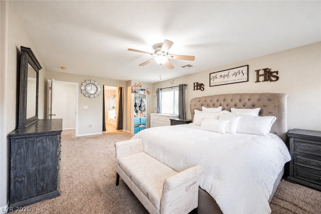 Plush carpeting anchors this spacious bedroom featuring an attached private bathroom suite.