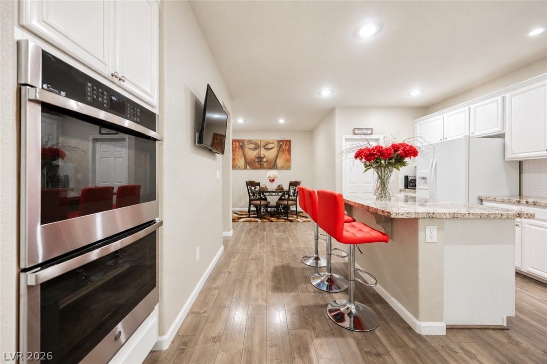 Polished hardwood floors lead through a modern kitchen featuring granite countertops and recessed lighting.