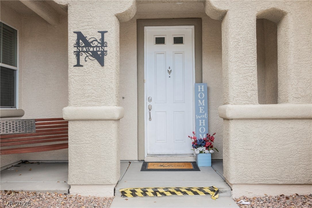 Thick stucco pillars frame a sheltered front entry featuring a classic paneled door.
