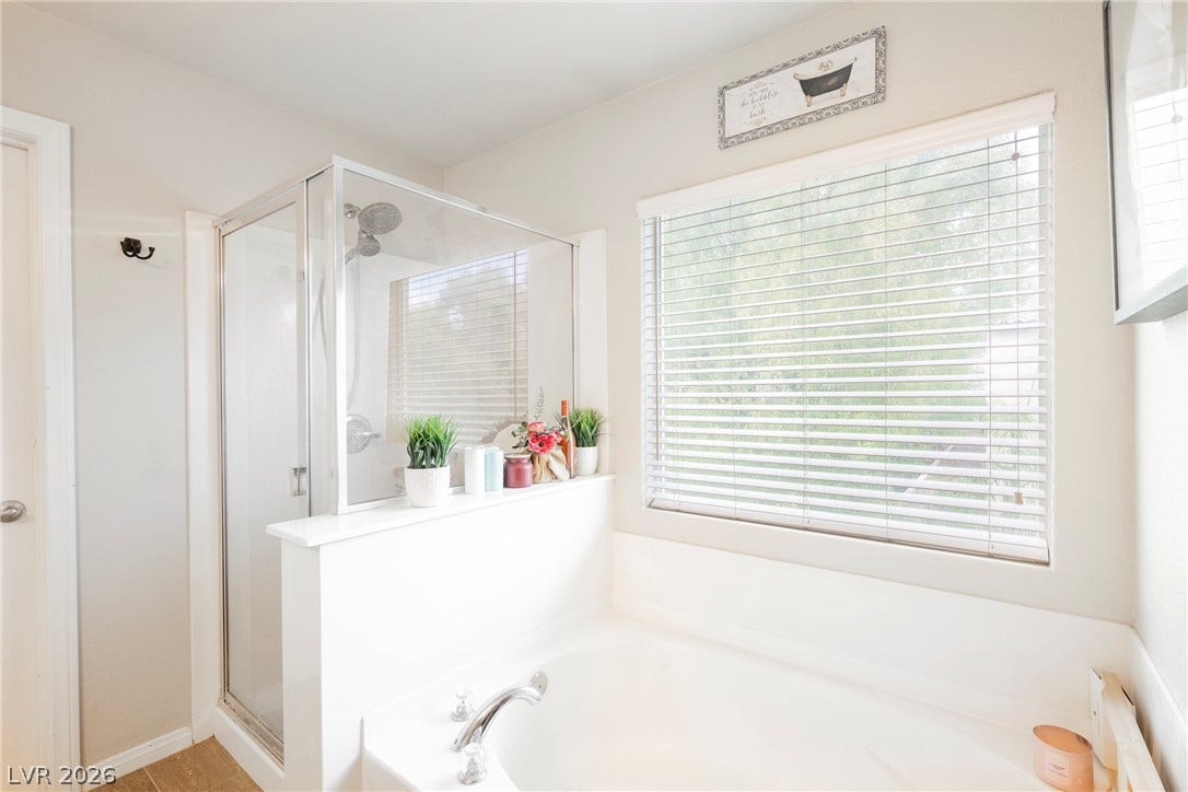 Natural light pours over the soaking tub and glass-enclosed shower.