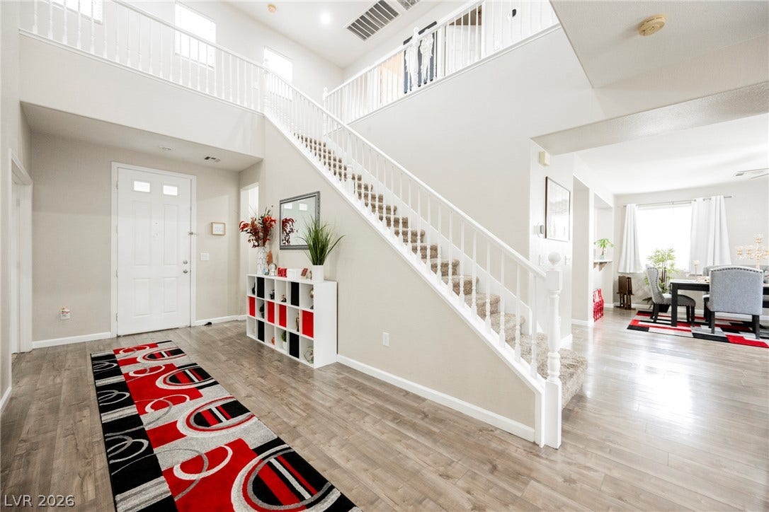 A grand entry foyer features high ceilings, durable wood-look flooring, and a sweeping staircase.