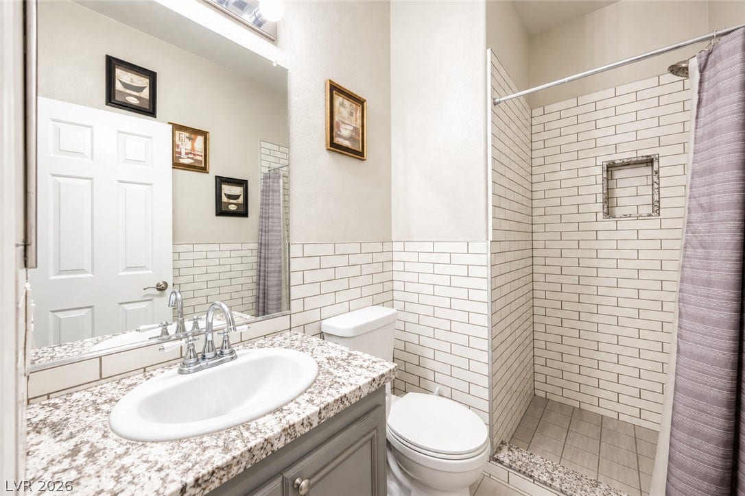 Polished granite countertops complement classic subway tiling in this refreshed secondary bathroom.