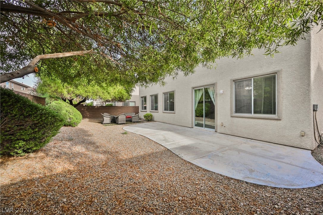 Mature trees shade a concrete patio alongside the low-maintenance backyard.
