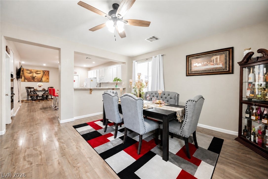 Warm wood flooring and an open layout connect the dining space to the nearby kitchen.