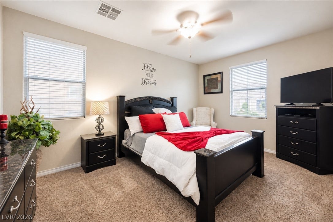 A comfortable bedroom features plush neutral carpeting and dual windows that maximize natural light.