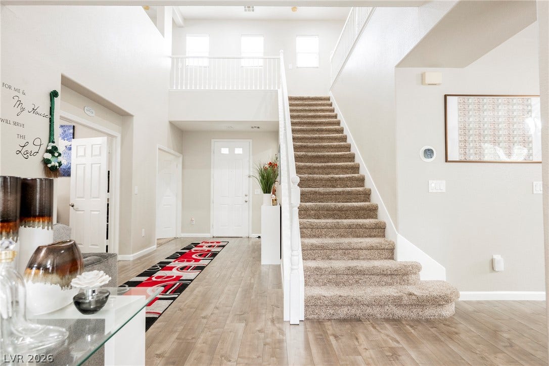 An inviting entrance foyer showcases wood-look flooring and a carpeted staircase leading to the upper level.