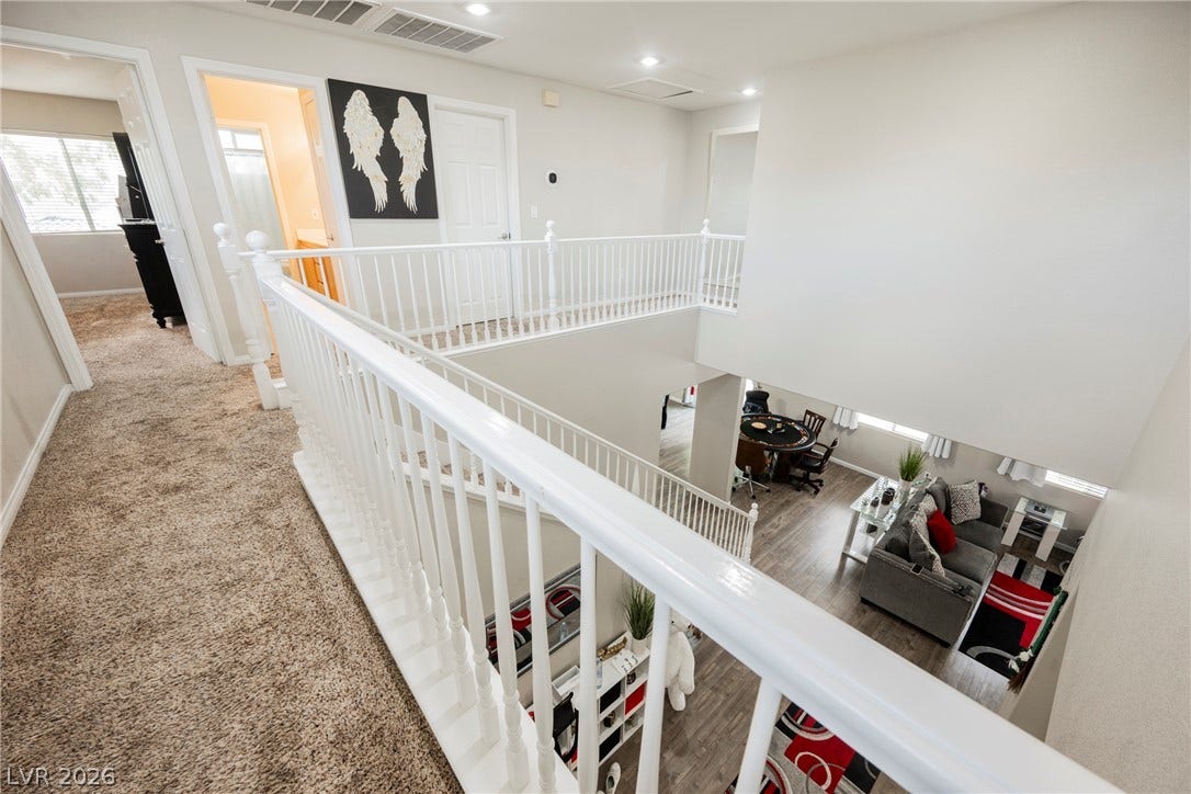 An upper hallway with classic balusters overlooks the lower level living space.