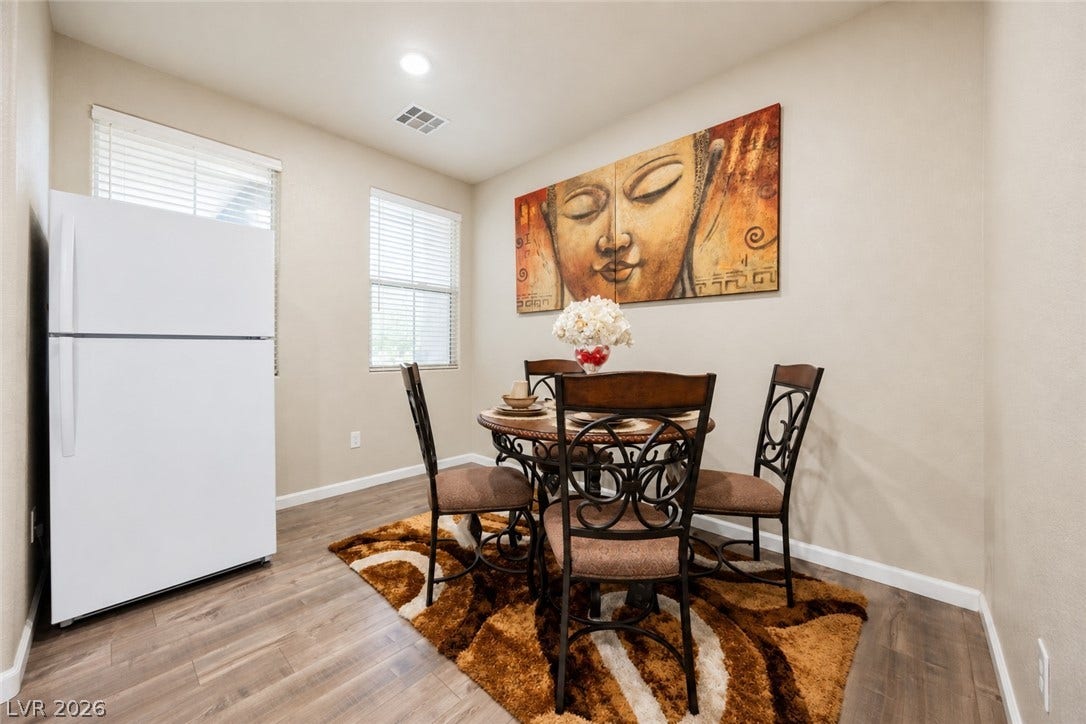 A cozy dining area features warm wood-look flooring and dual windows allowing natural light.