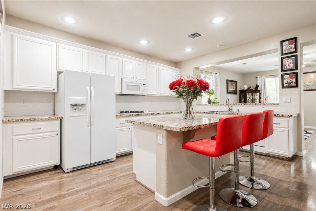 Gleaming stone countertops and recessed lighting highlight this modern culinary workspace with wood floors.