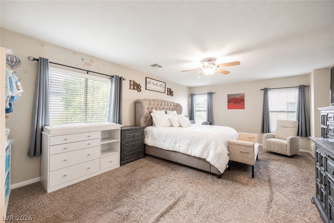 Plentiful natural light streams through multiple windows into this spacious carpeted bedroom.