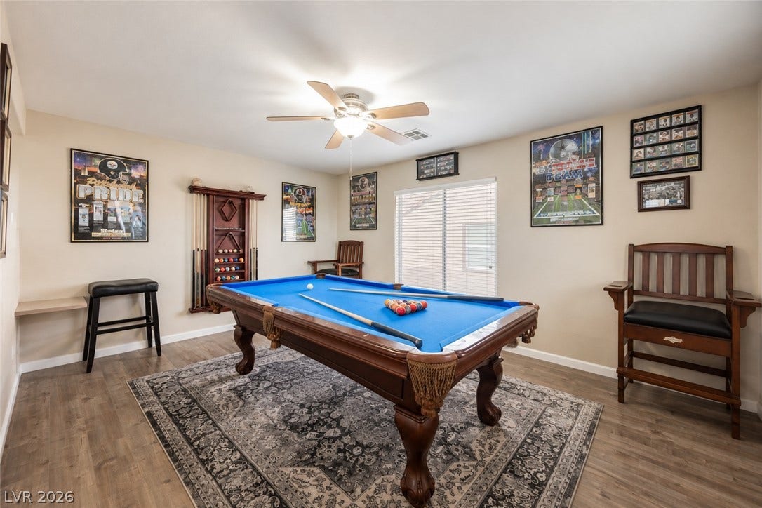 A spacious recreation room features smooth wood-style flooring and an abundance of natural light.